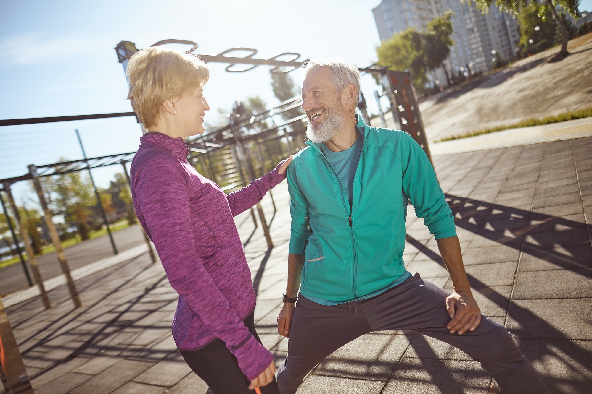 Happy and healthy. Smiling mature family couple in sportswear doing gymnastics together at outdoor