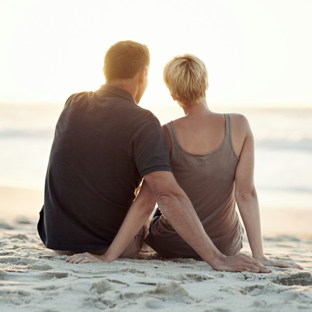 Sunset love. A loving couple sitting on the beach - rear view.