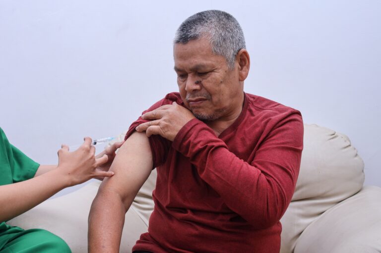 Doctor making injection to senior patient in clinic