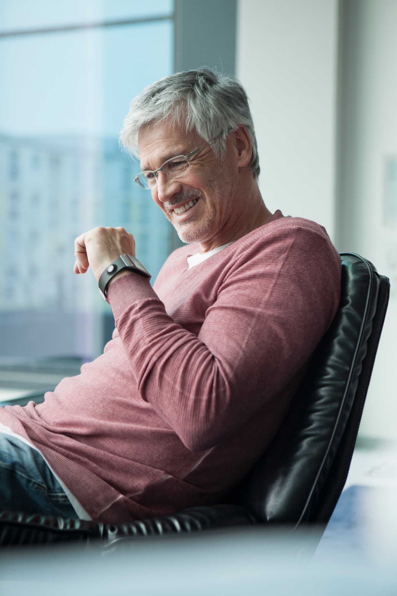 Smiling man with smartwatch sitting in a leather chair