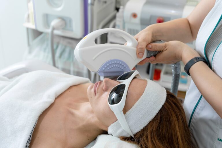 Woman receiving laser facial treatment, removing pigmentation at cosmetic clinic.