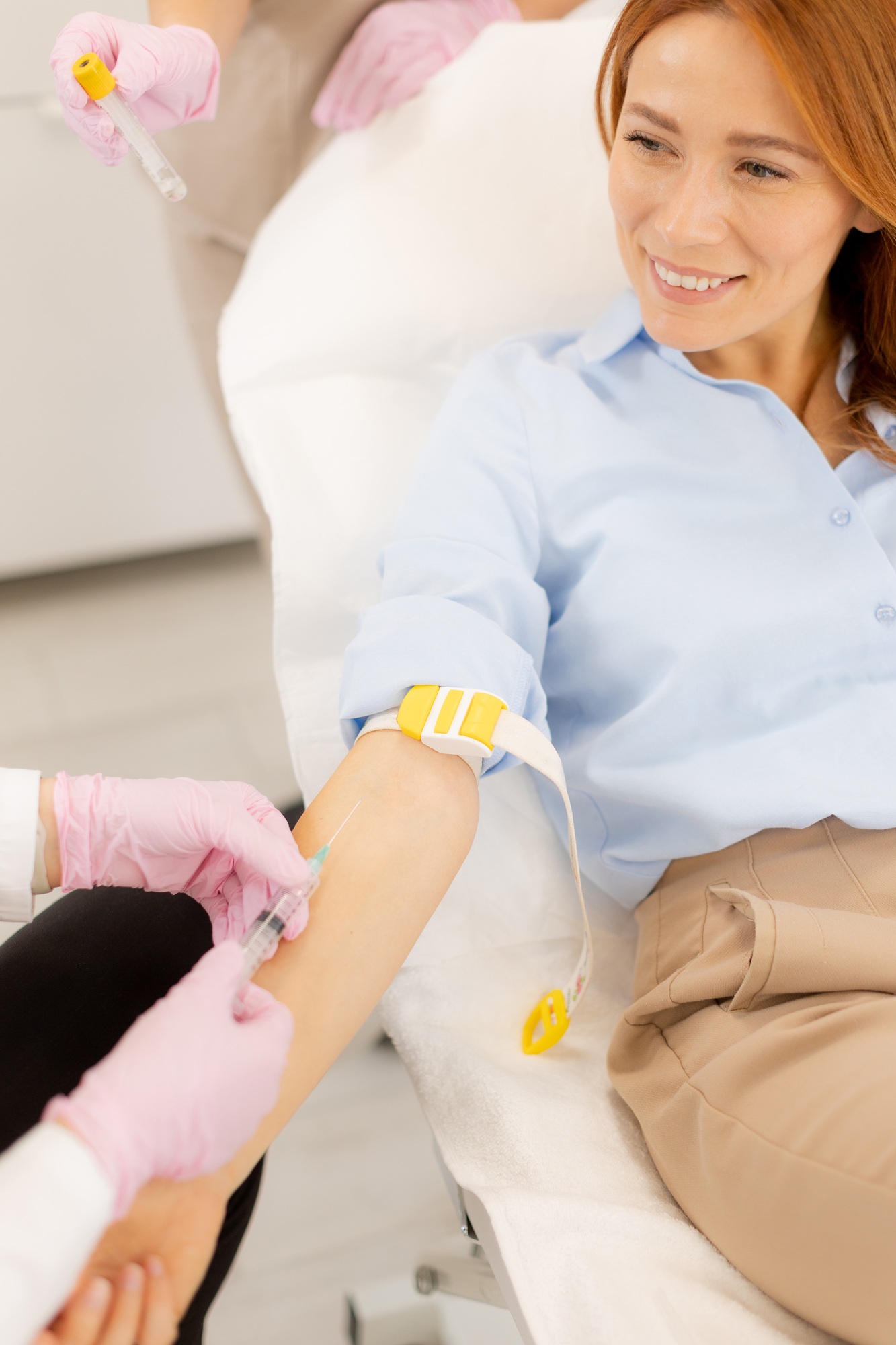 Woman smiling as a healthcare professional prepares to draw blood in a modern clinic environment