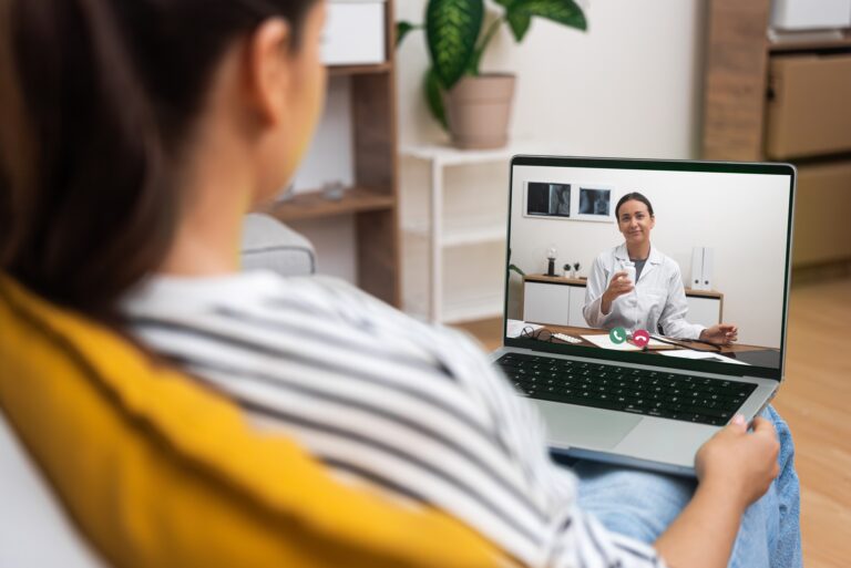a-young-woman-in-a-home-environment-listens-to-a-doctor-on-a-telehealth-video-call-on-her-laptop--768x513